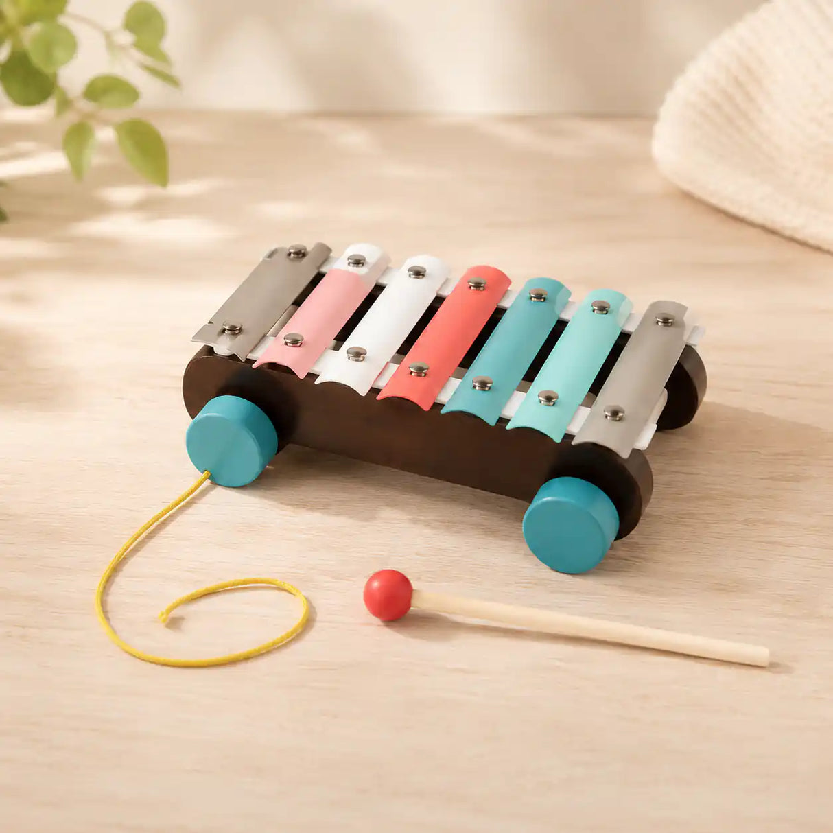 Child seated at a wooden table stacking a hexagon ring on the wooden Montessori stacker next to the rainbow puzzle