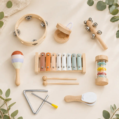 Wooden musical instrument set with xylophone, tambourine, triangle and shakers in a natural wood tray on a cream background