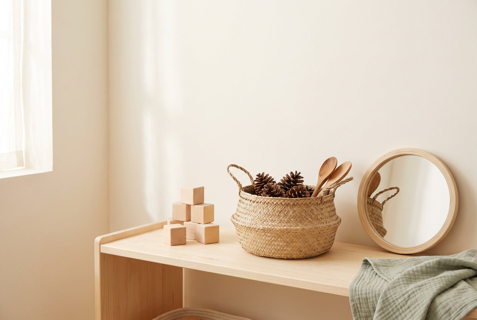 A simple, affordable Montessori shelf with plain wooden blocks, a basket of pinecones and wooden spoons, and a small mirror