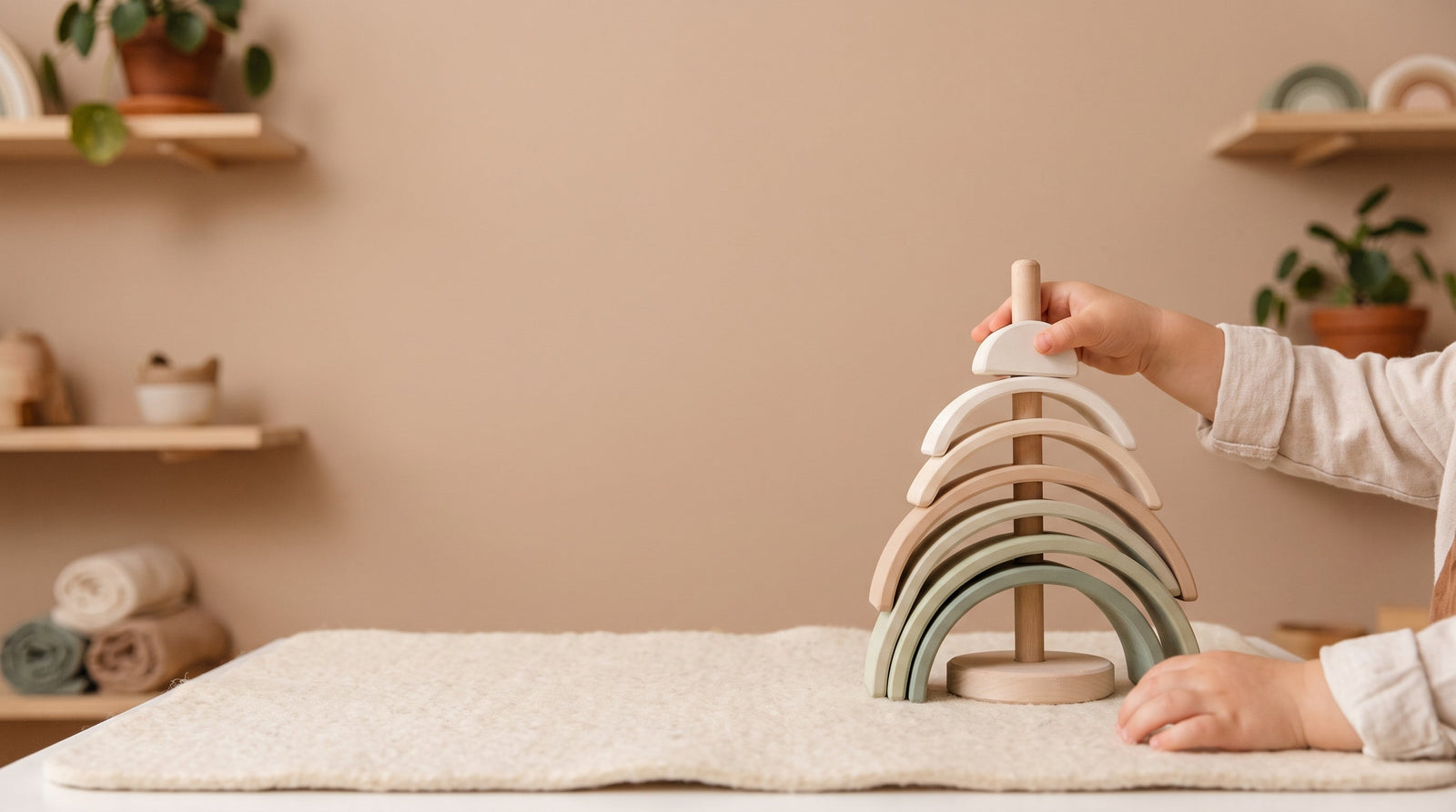 Toddler's hands stacking a wooden rainbow tower in Montessori balancing play
