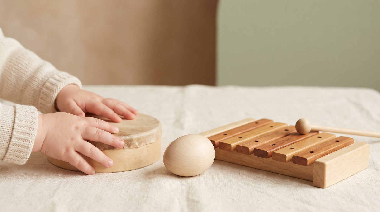Toddler's hands exploring simple wooden musical instruments in calm Montessori sensory play