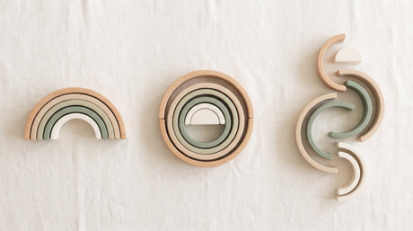 A wooden rainbow stacker arranged several different ways, showing open-ended play