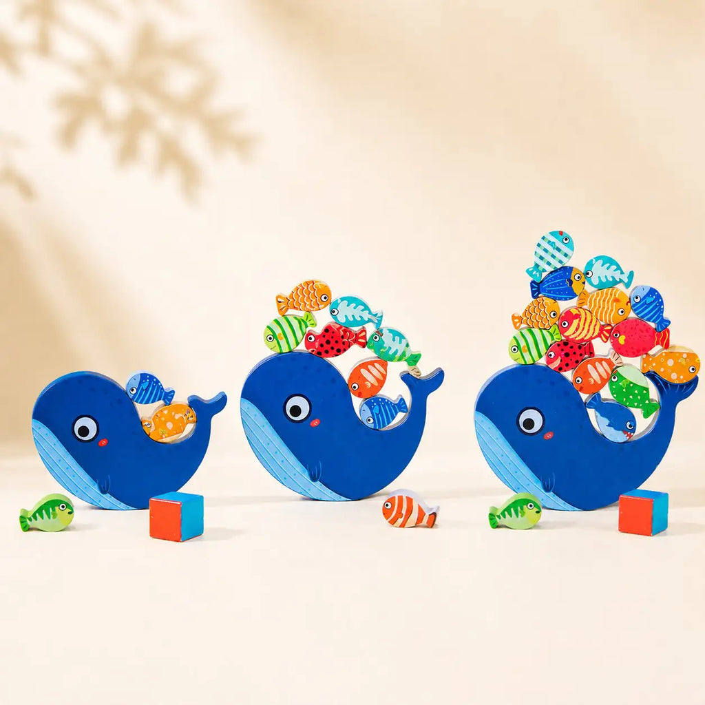 Wooden whale balancing toy shown in three sizes — small, medium and large