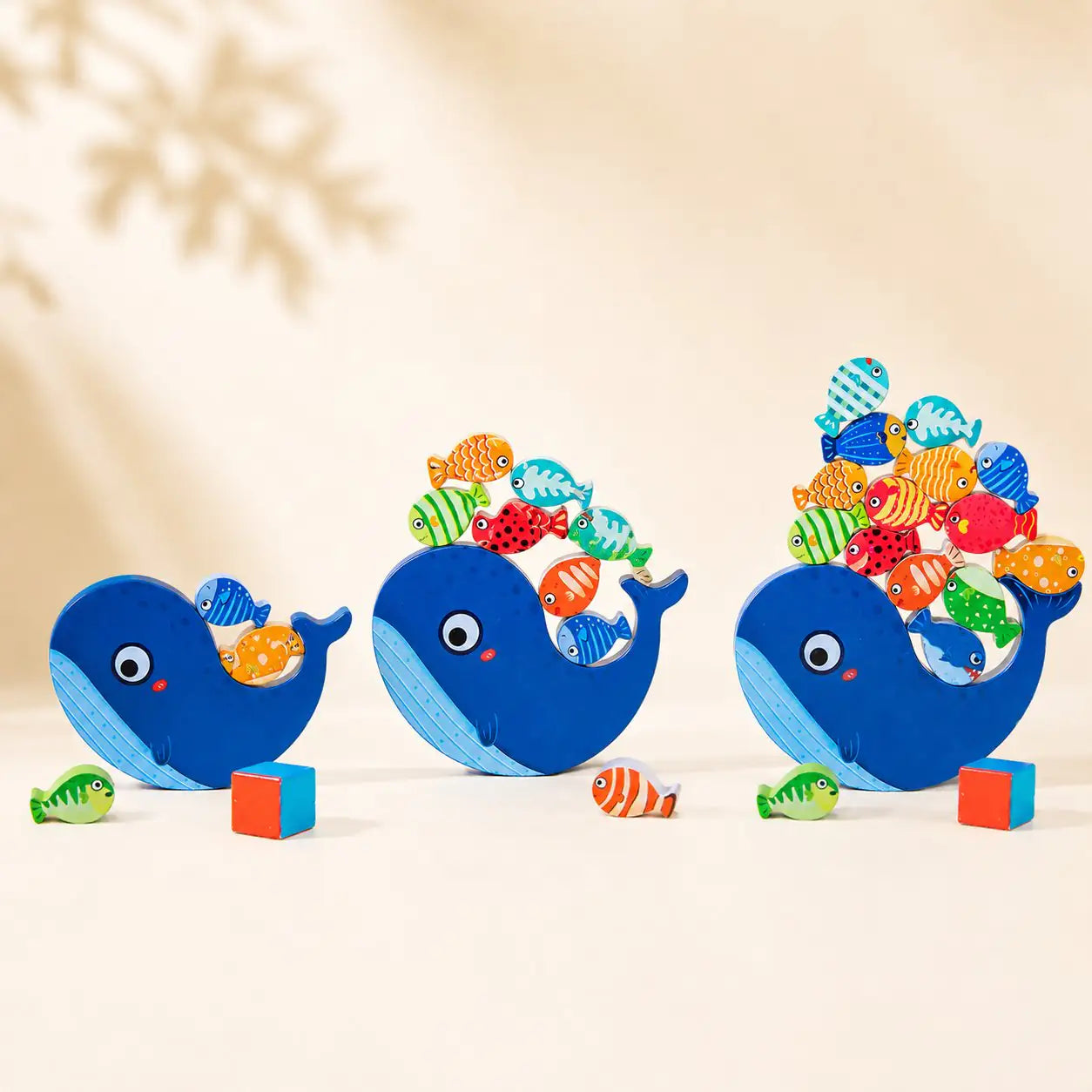 Wooden whale balancing toy shown in three sizes — small, medium and large