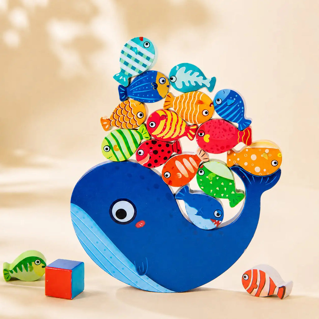 Wooden whale balancing toy fully stacked with colorful fish balanced along the whale's back