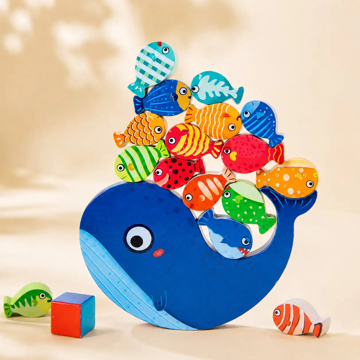 Wooden whale balancing toy fully stacked with colorful fish balanced along the whale's back