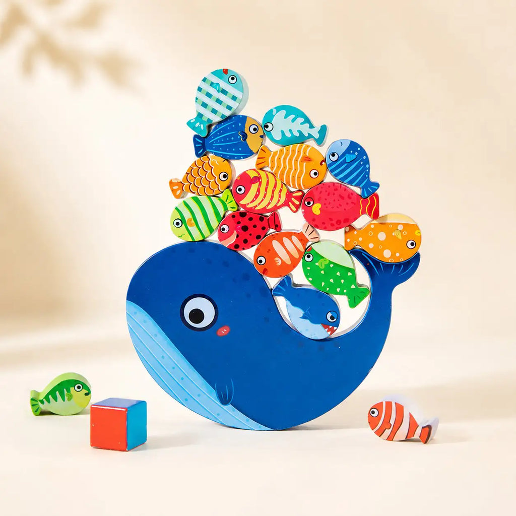 Wooden whale balancing toy with the small whale piece nested in the belly cutout on cream