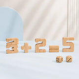 Young boy stacking a wooden 8 onto a number block tower with other natural wood numbers and dice spread across the table