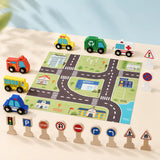 Child's hand placing a wooden school bus on the printed city play mat next to ambulance, police car, and traffic signs