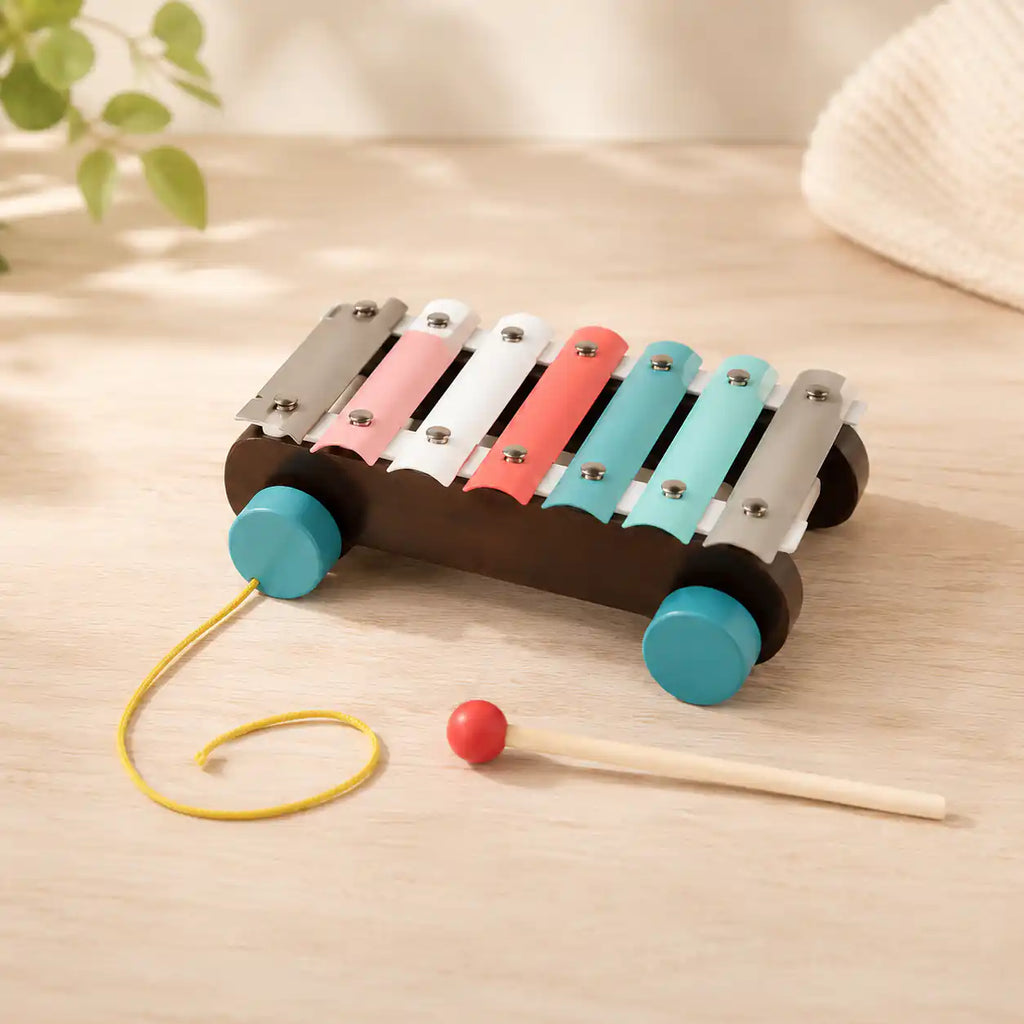 Child seated at a wooden table stacking a hexagon ring on the wooden Montessori stacker next to the rainbow puzzle