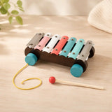 Child seated at a wooden table stacking a hexagon ring on the wooden Montessori stacker next to the rainbow puzzle