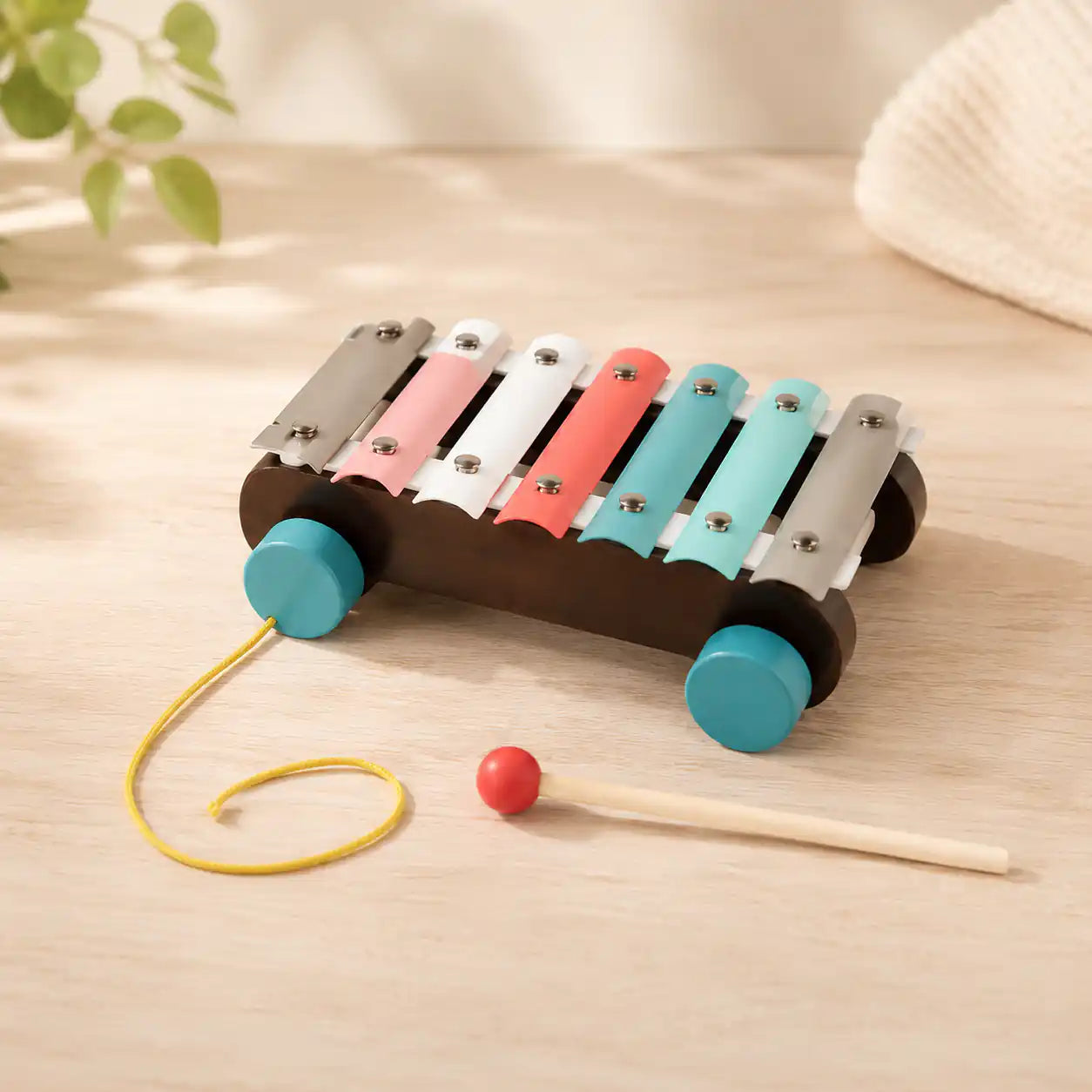 Child seated at a wooden table stacking a hexagon ring on the wooden Montessori stacker next to the rainbow puzzle