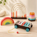 Wooden counting abacus with 4 golden arches and coral, pink, cream, and orange wooden beads on a dark wood base