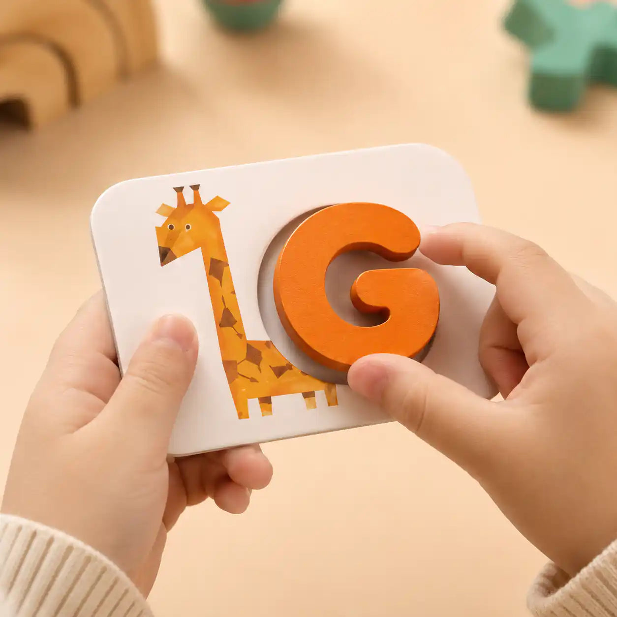 Close-up of toddler hands fitting the wooden G letter into a giraffe alphabet flashcard