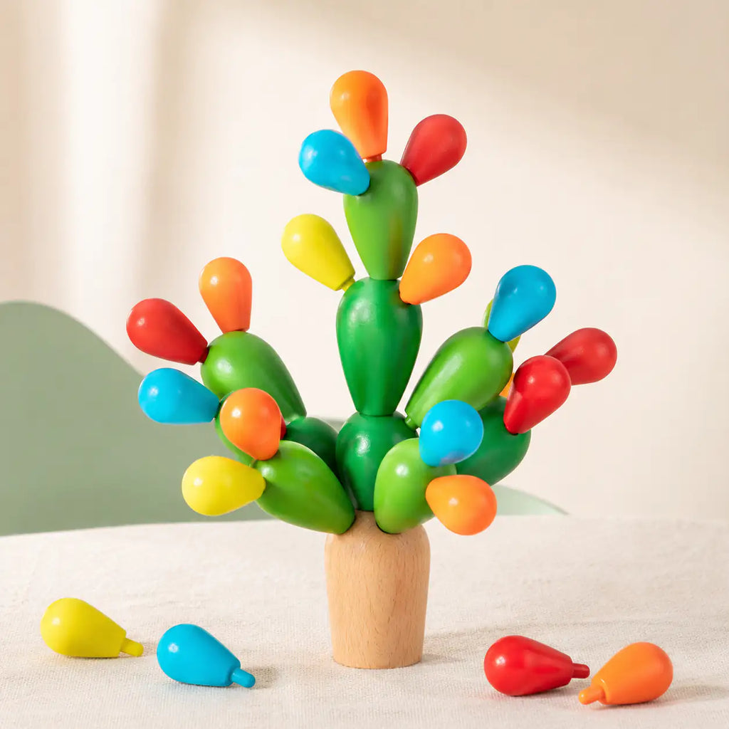 Wooden balancing cactus stacking toy with green cactus pieces and colorful wooden fruits on a cream background