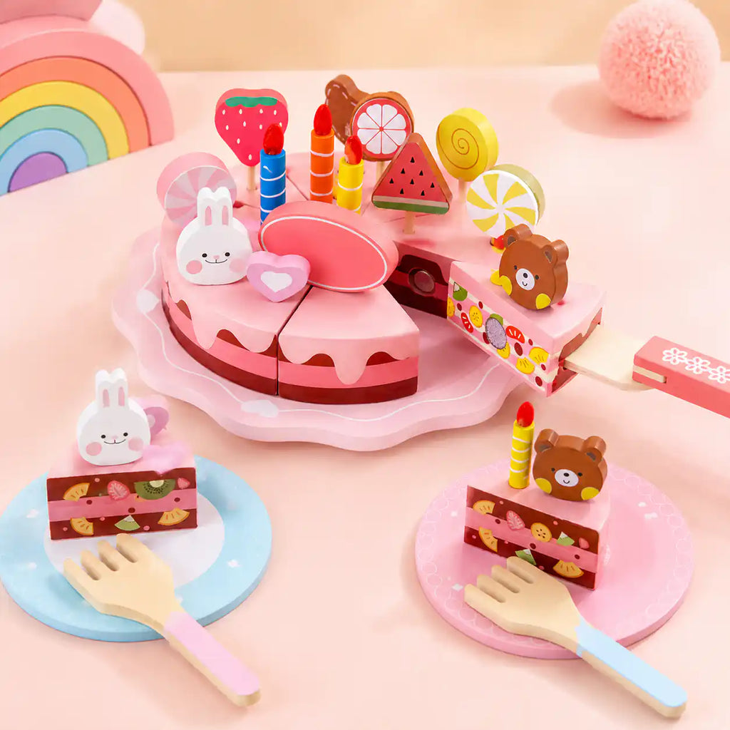 Wooden birthday cake with a slice being lifted on a wooden knife and two plated slices nearby