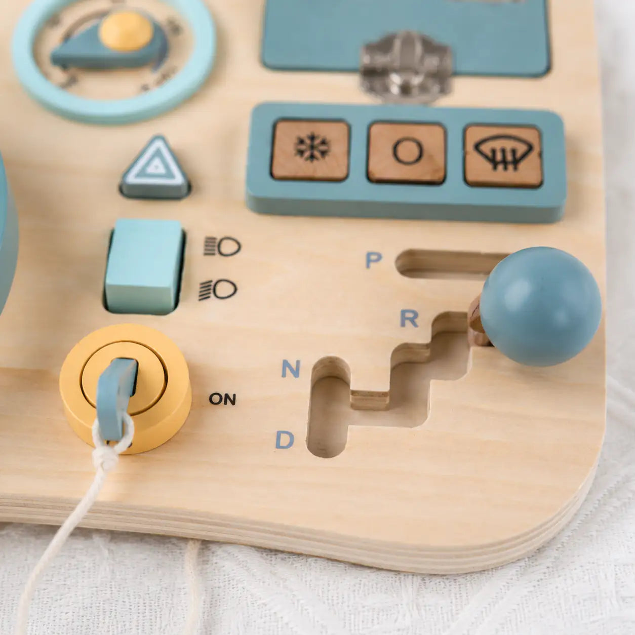 Toddler hands turning the steering wheel and gear shifter on the wooden busy board mini