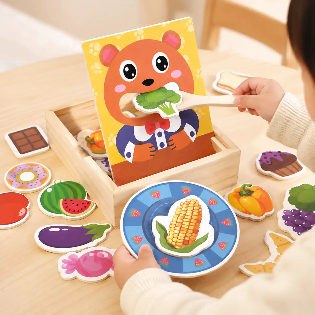 Toddler hands using a wooden spoon to feed a broccoli piece to the wooden bear panel during pretend mealtime play