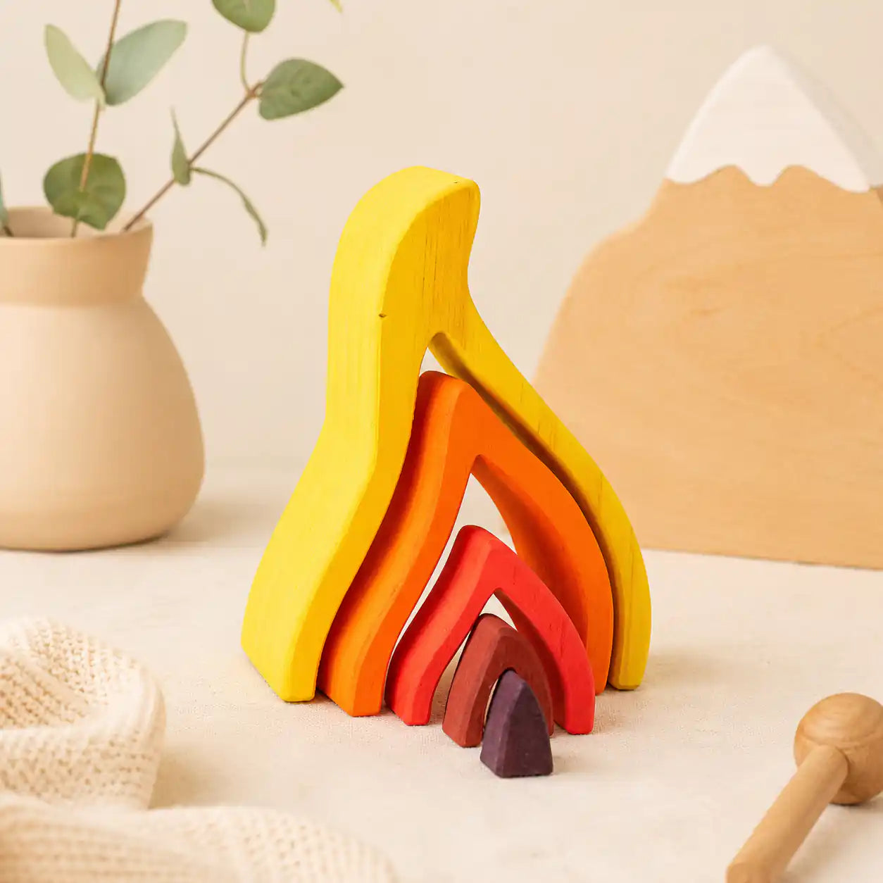 Wooden flame puzzle pieces arranged in an open layered configuration showing creative play possibilities
