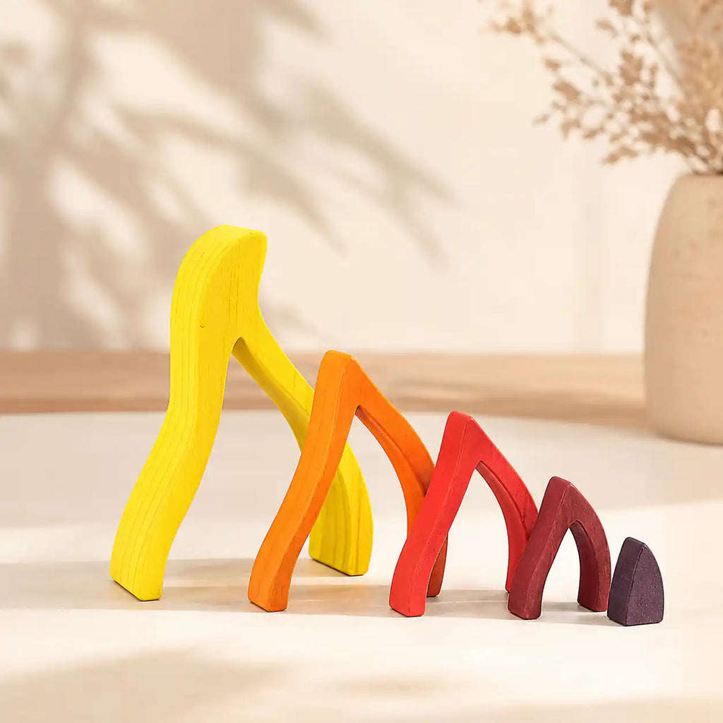 Five wooden flame puzzle pieces lined up as separate arches showing graduated sizes from yellow to dark ember