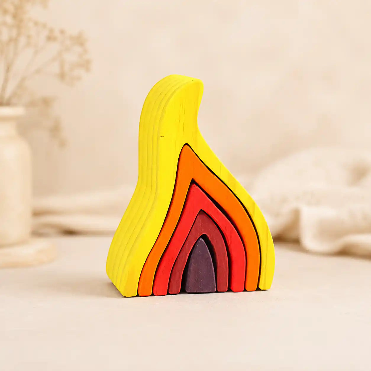 Wooden flame stacking puzzle in yellow, orange, red, and ember tones on a warm cream background, Waldorf-inspired for ages 4+