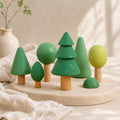 Wooden forest tree set arranged by height on a soft cream surface showing graduated tree sizes