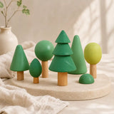 Wooden forest tree set arranged by height on a soft cream surface showing graduated tree sizes