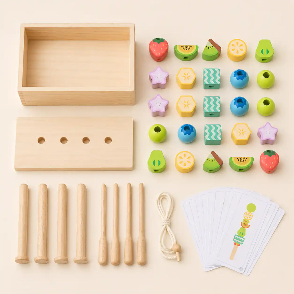 Wooden fruit bead set components laid flat with wooden box, dowels, lacing sticks, string, 25 fruit beads, and pattern cards
