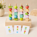 Four wooden dowels with stacked fruit beads on a wooden box base, with three pattern cards leaning in front showing bead sequences
