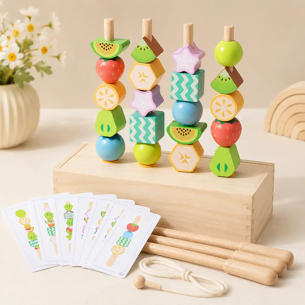 Wooden fruit bead stacking set with 4 standing dowels holding colorful fruit beads in a solid wood box base, pattern cards in the foreground