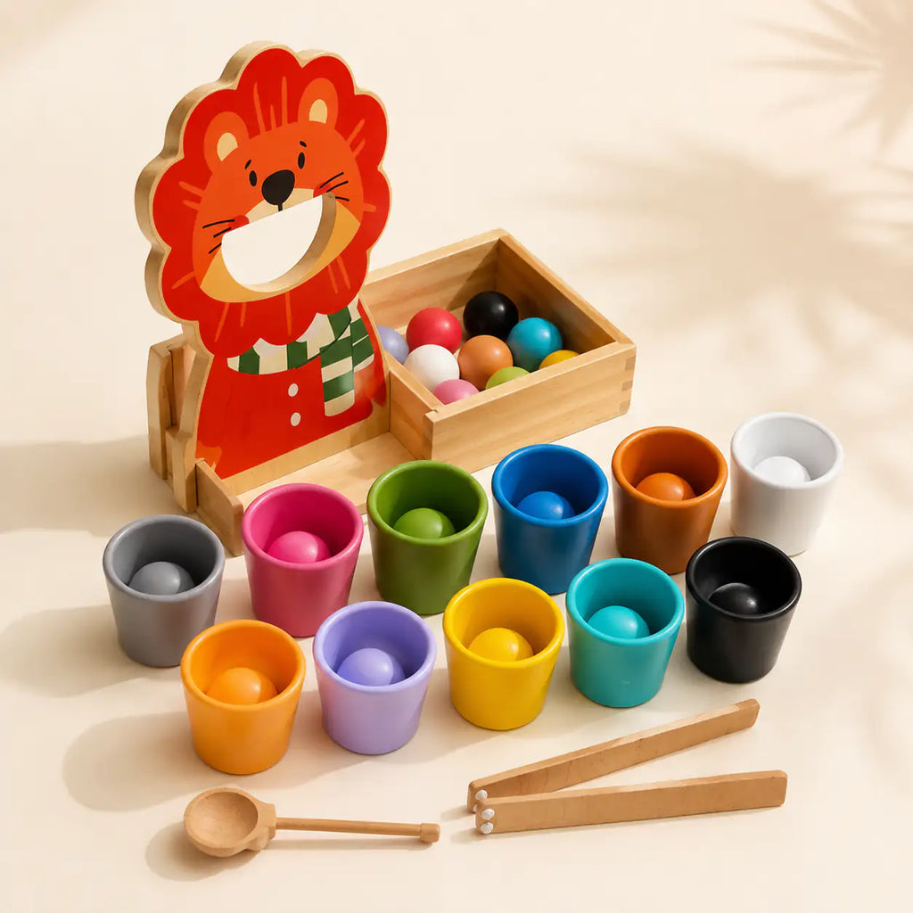 Wooden lion color sorter with 12 colored balls, cups, scoop and tongs on a cream background