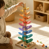 Color-sorted marbles racing down the rainbow tiers of the wooden marble run music tree