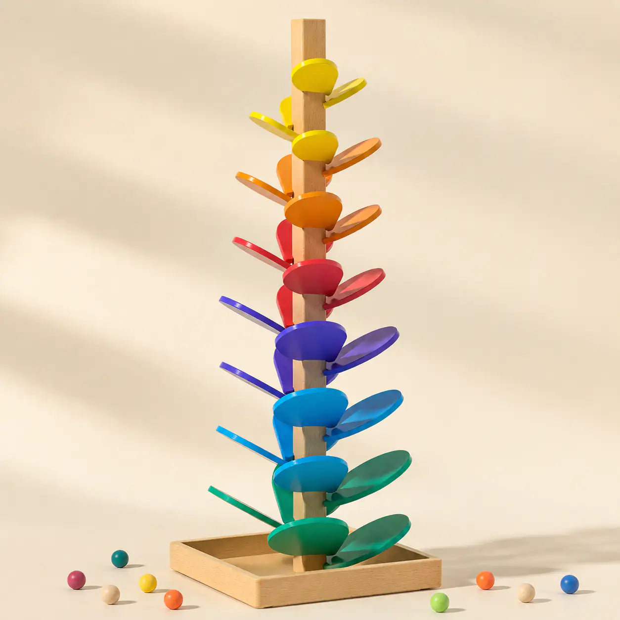 Wooden marble run music tree with rainbow leaf chimes on a cream background