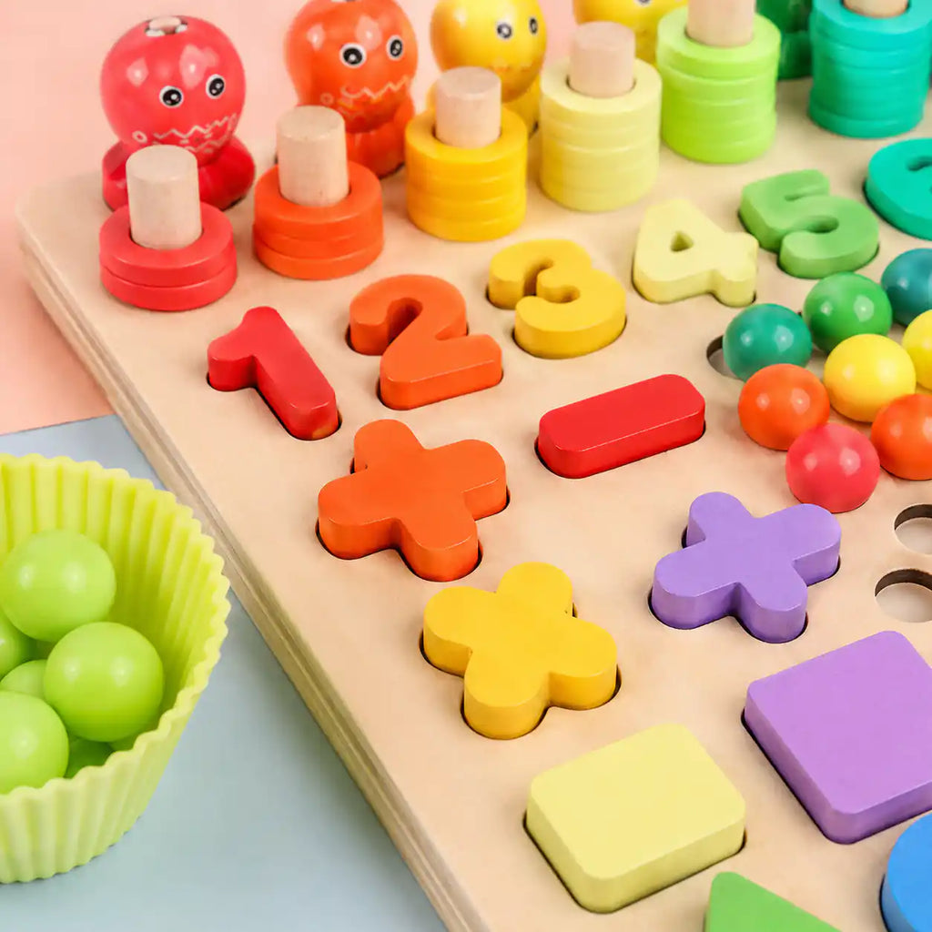 Close-up of the wooden Montessori learning board showing chunky rainbow numbers 1 through 5, addition and subtraction symbols, and counting tower pegs in red, orange, and yellow