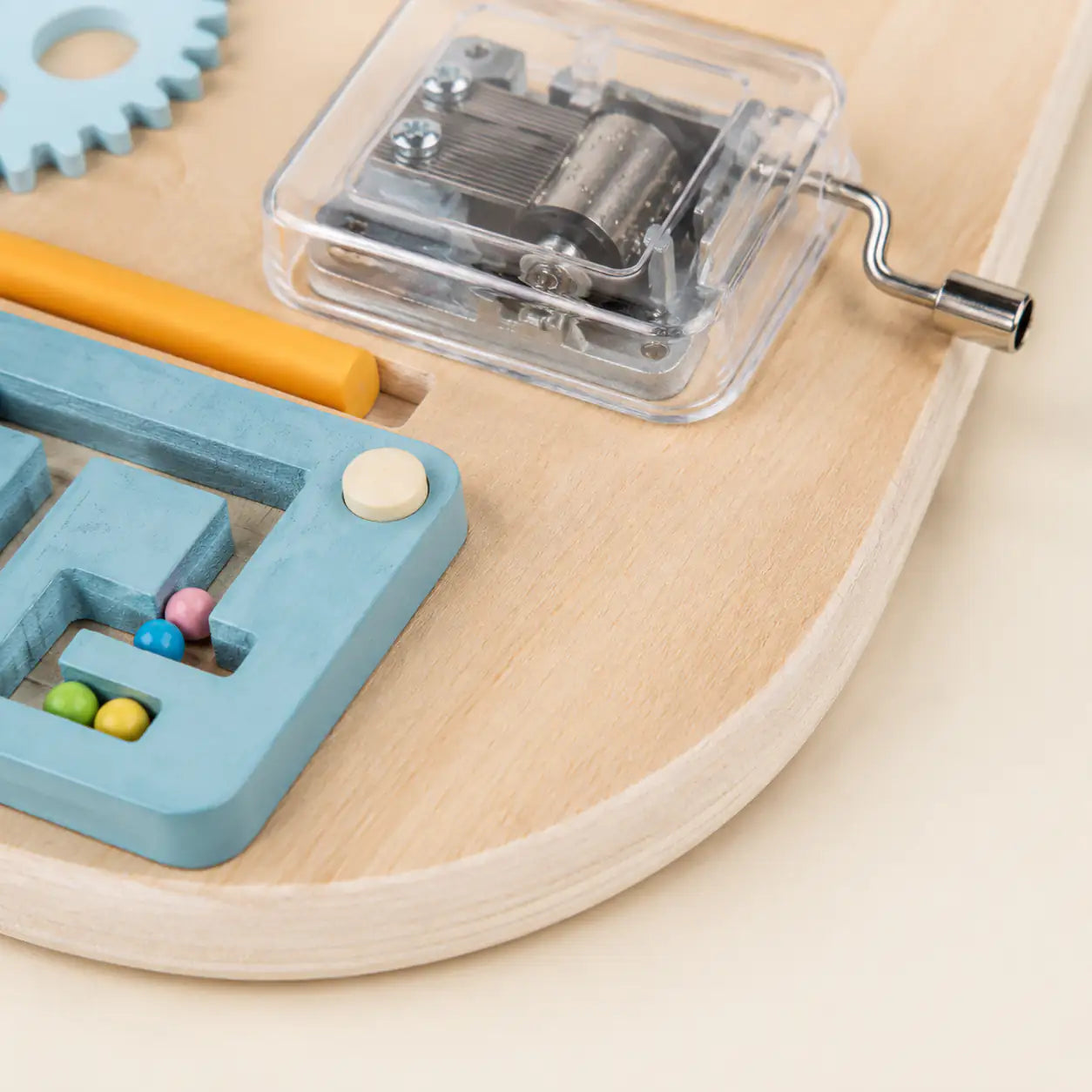 Close-up of the interlocking wooden gears, teaching clock and gauge dials on the Montessori busy board