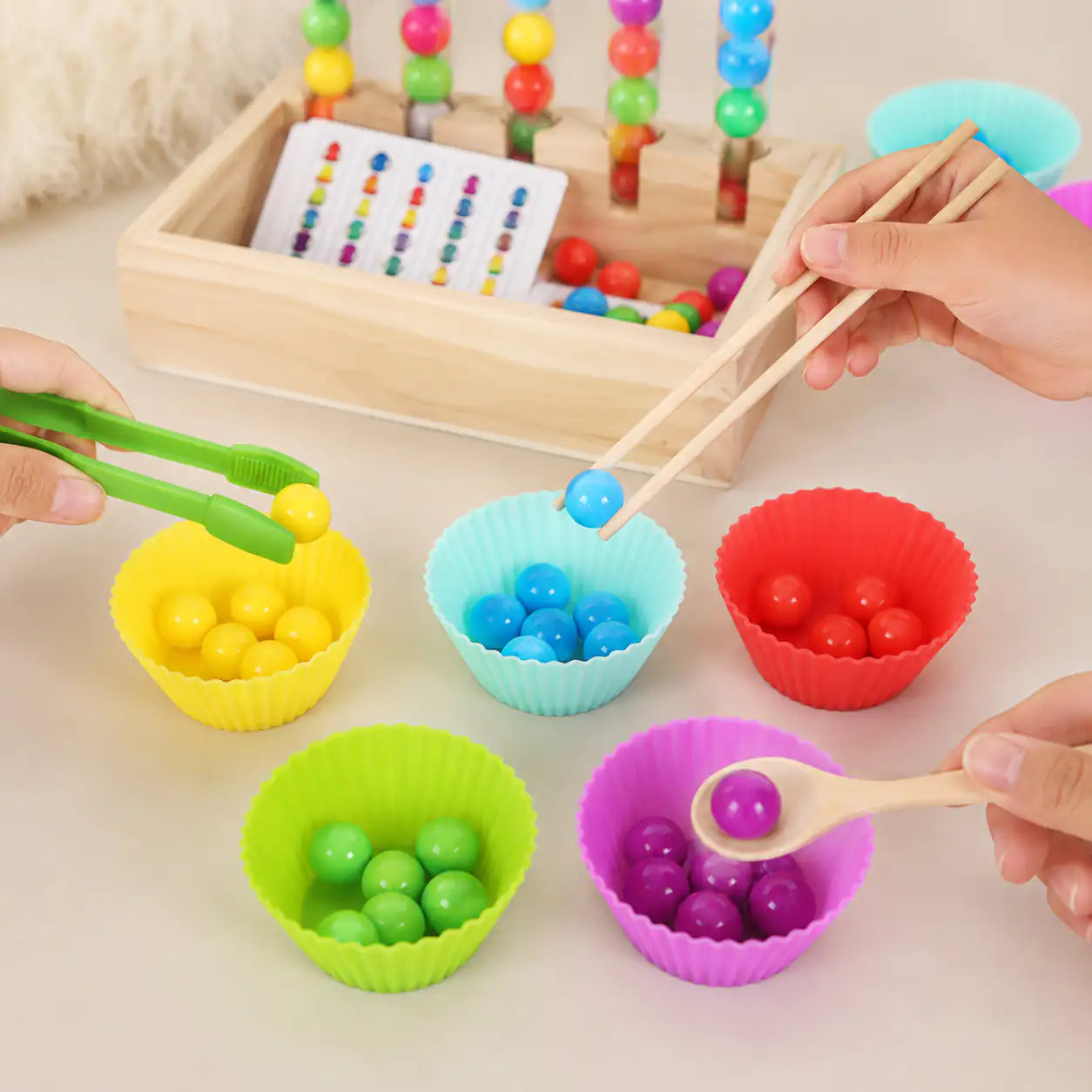 Close-up of the wooden storage box, clear test tubes and pastel silicone bowls of the bead sorting set