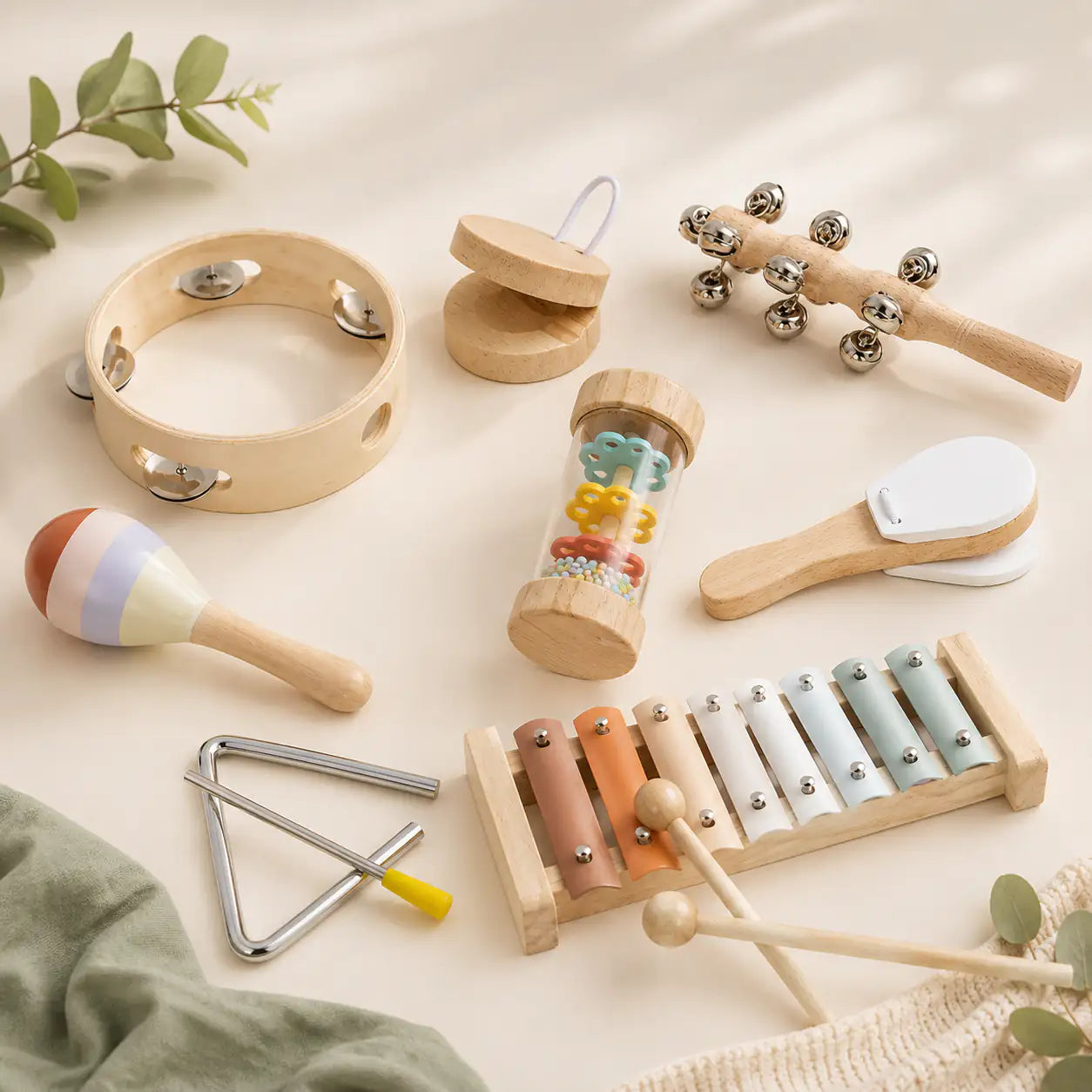 Wooden tambourine, triangle, bell stick and maraca laid out beside the natural wood tray
