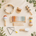 Wooden musical instrument set with xylophone, tambourine, triangle and shakers in a natural wood tray on a cream background