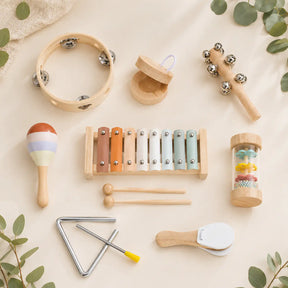 Wooden musical instrument set with xylophone, tambourine, triangle and shakers in a natural wood tray on a cream background