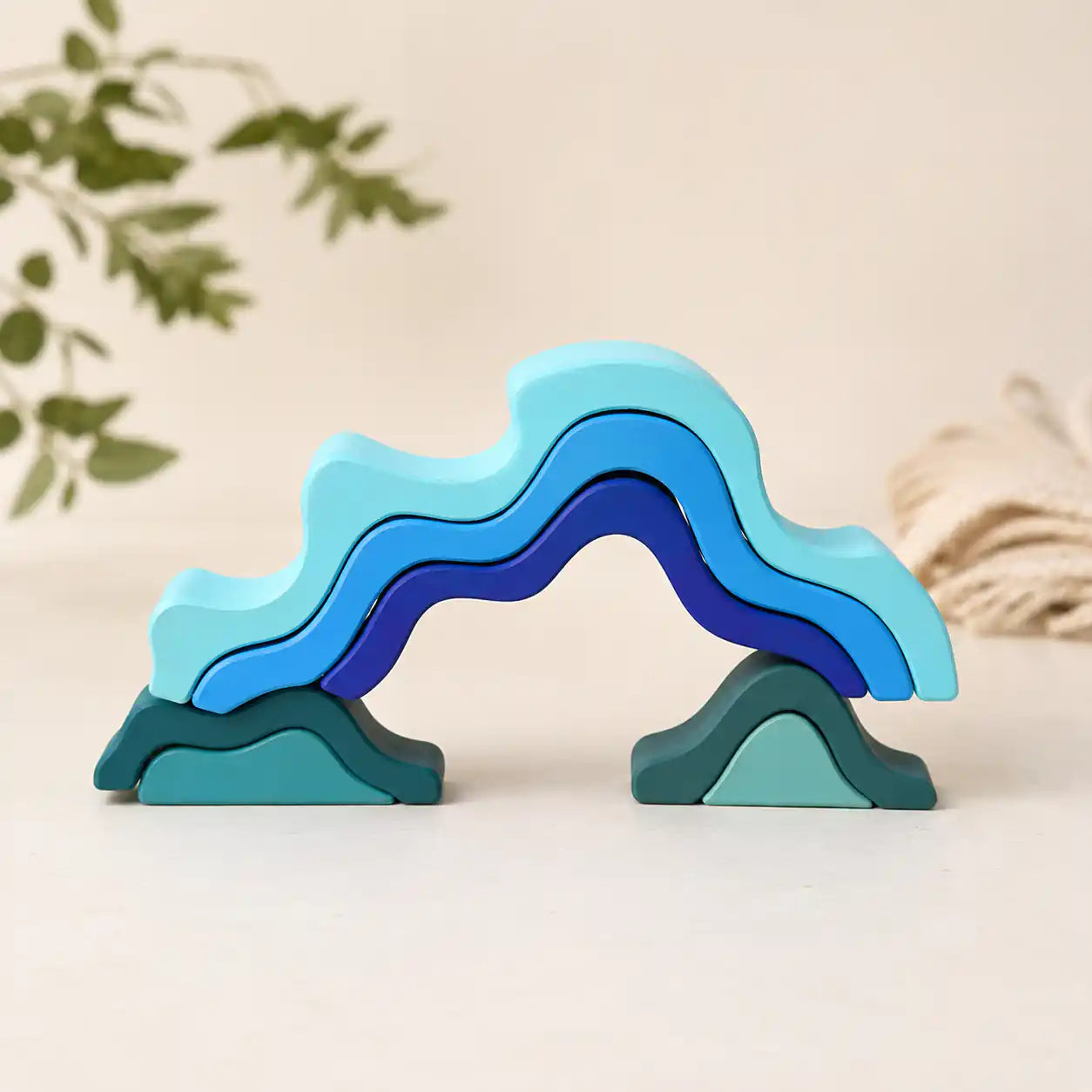 Small hands placing a wooden wave piece onto the ocean wave stacker on a warm neutral surface