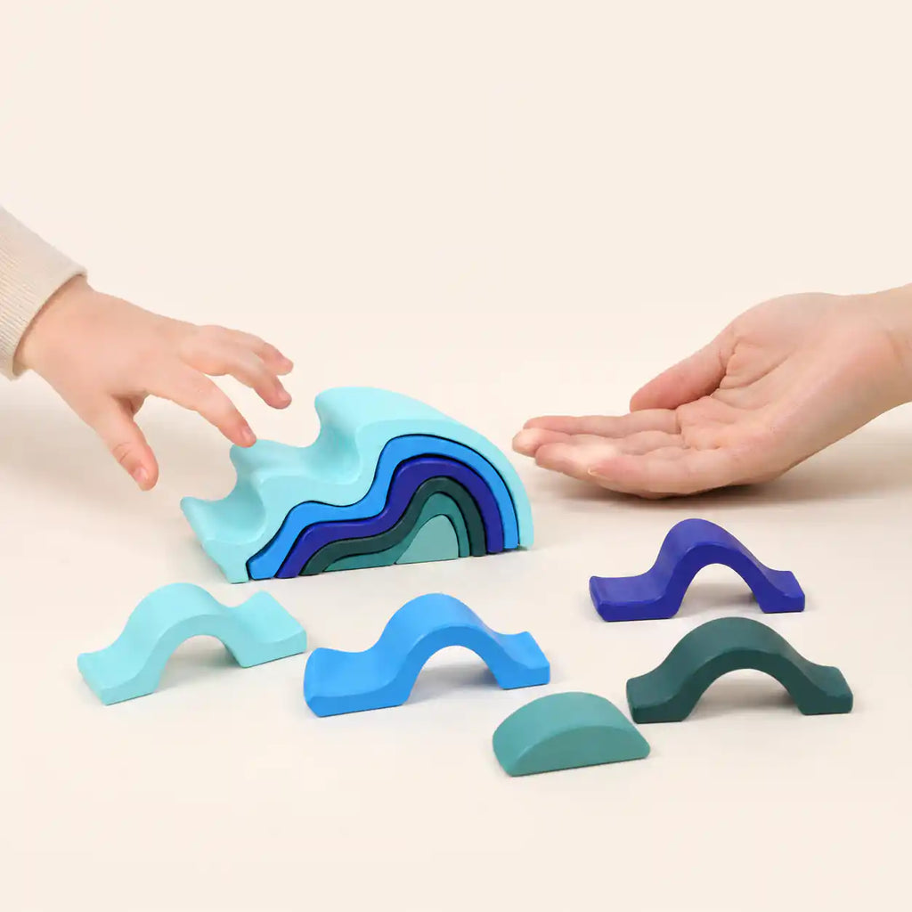 Close-up of a single wooden wave stacker piece showing painted finish and smooth curve