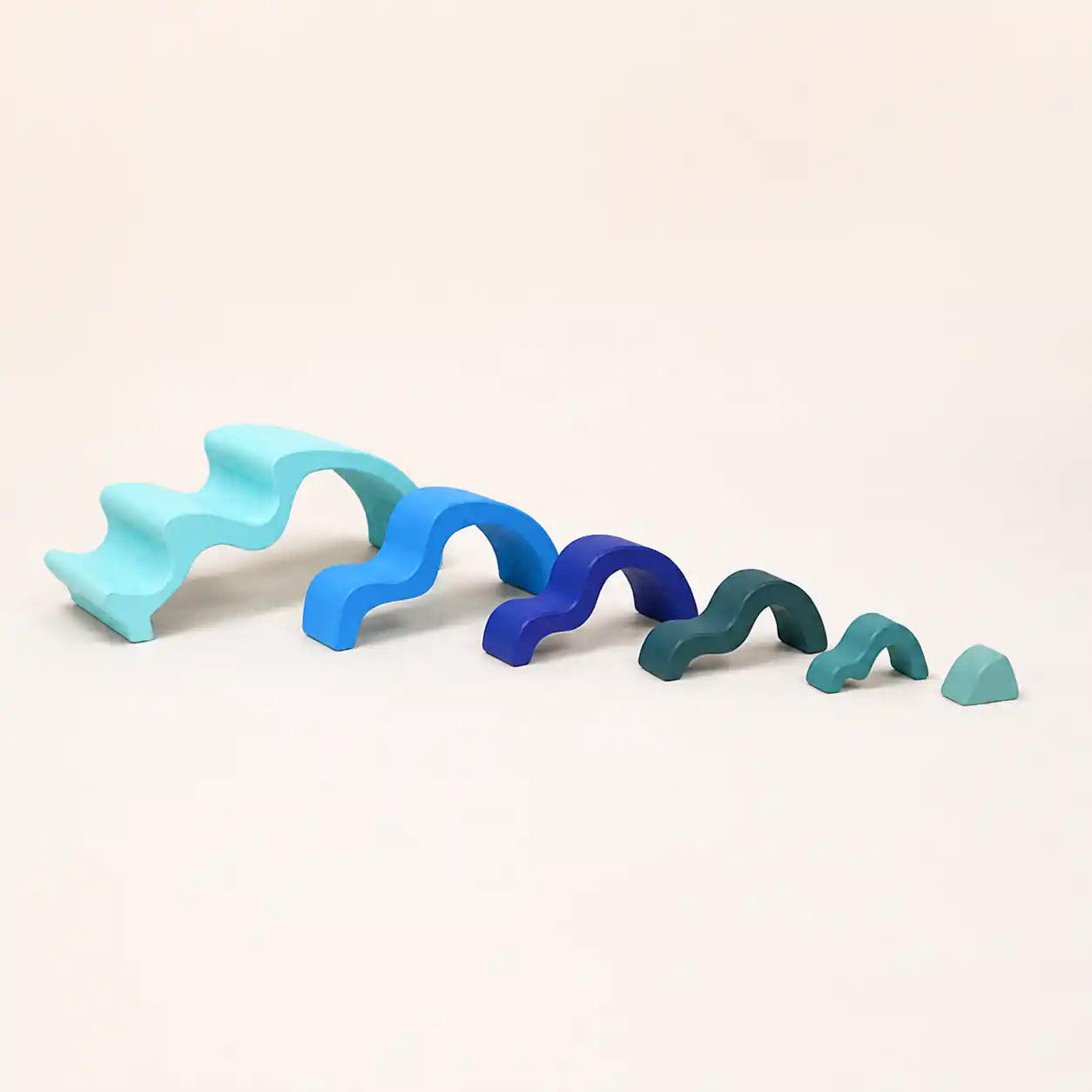 Wooden ocean wave stacker pieces separated and arranged on a cream surface showing each layer