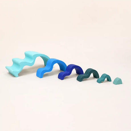 Wooden ocean wave stacker pieces separated and arranged on a cream surface showing each layer