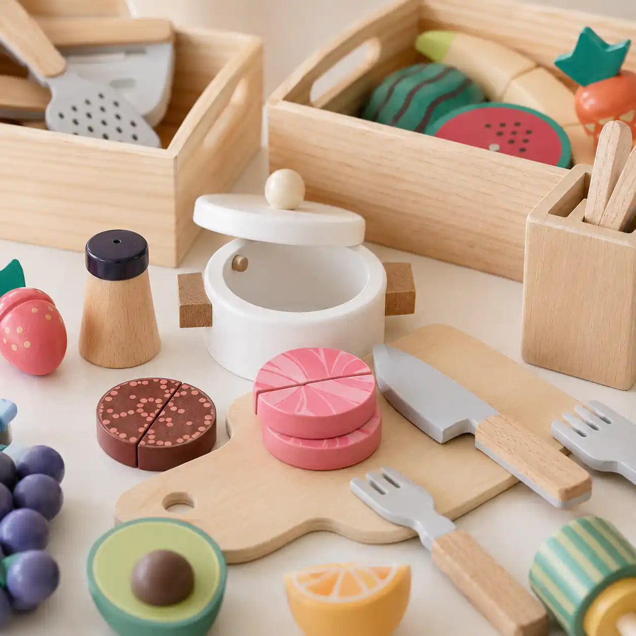 Close-up of wooden play food cooking scene with pot, knife, and pretend ingredients