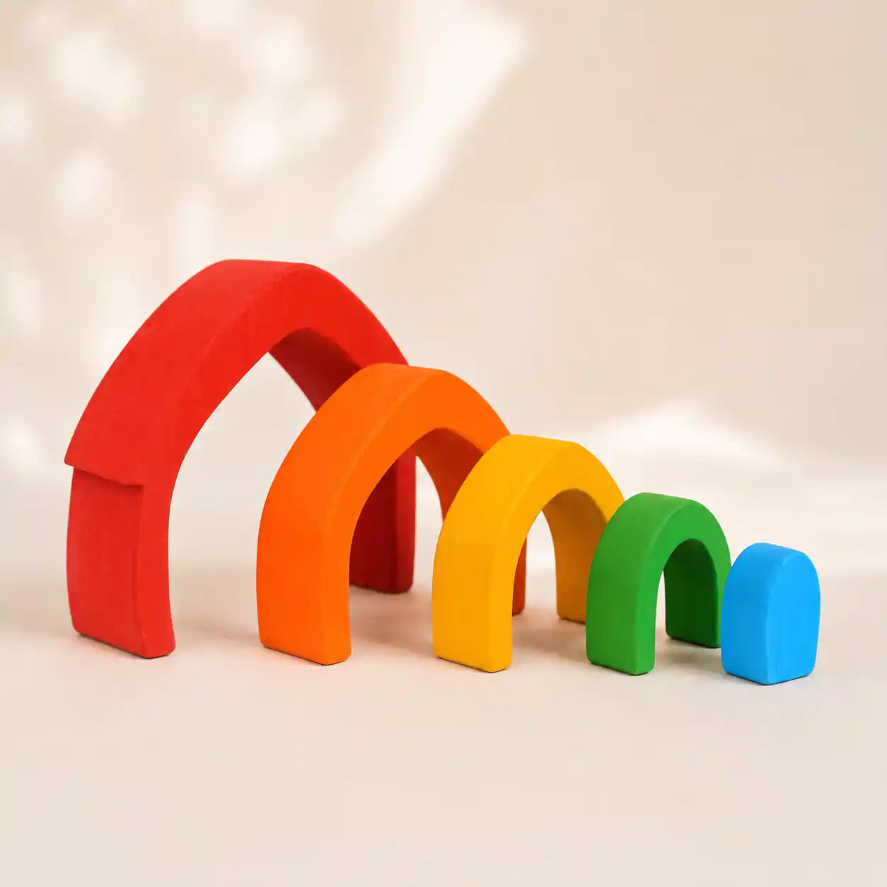 Side angle of wooden rainbow arch stacker showing graduated arch sizes and rainbow color order