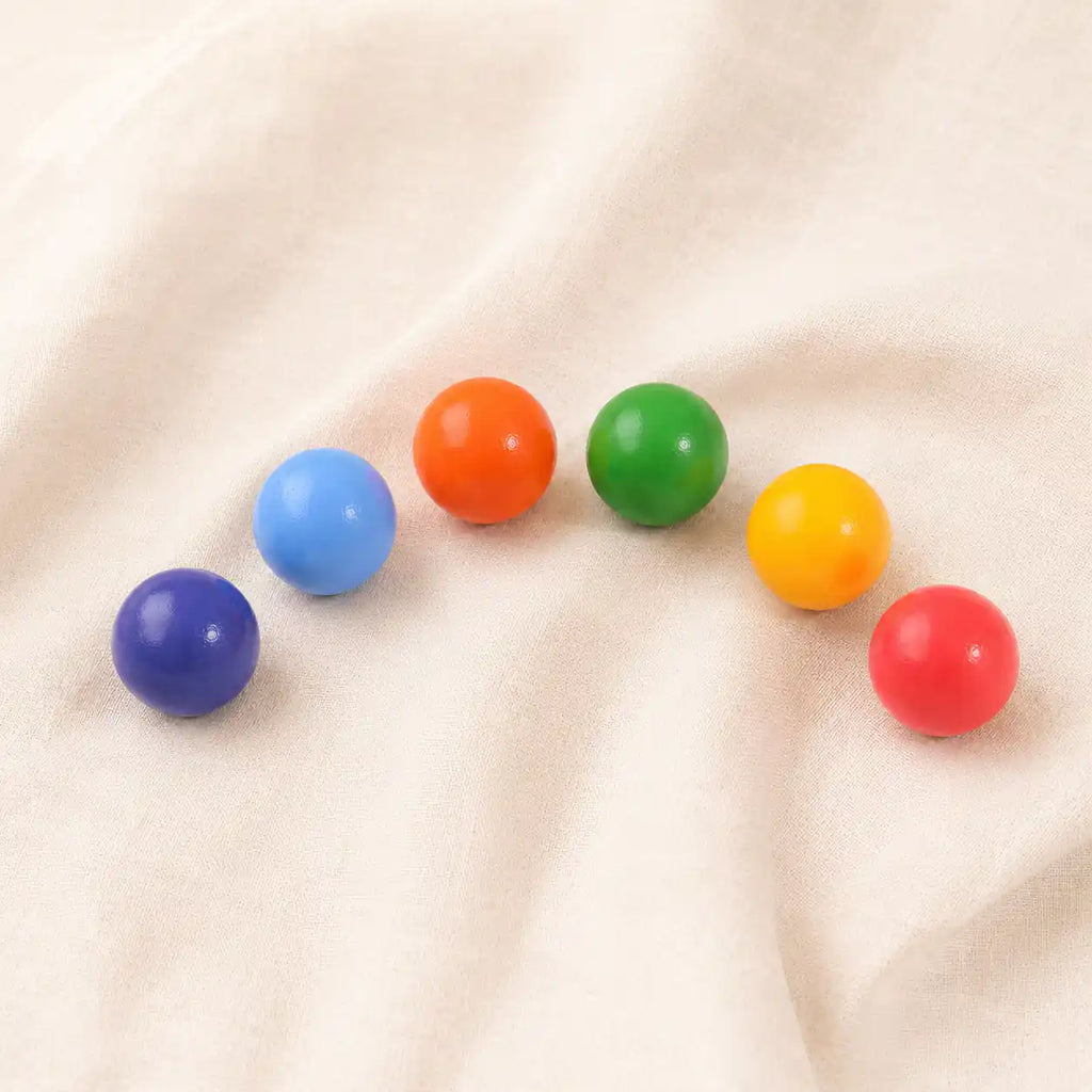 Wooden rainbow balls lined up by color showing the full rainbow gradient