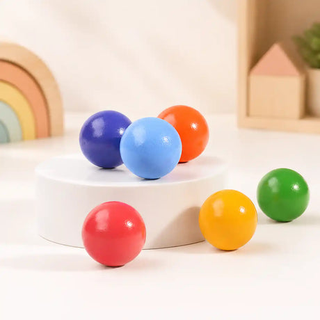 Wooden rainbow balls clustered together on a soft cream surface, hero shot