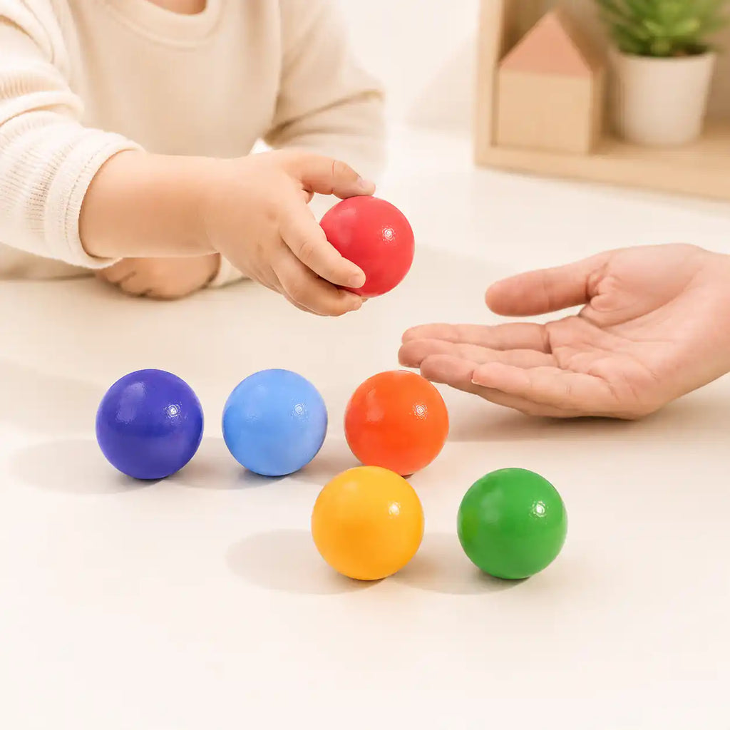 Wooden rainbow balls styled in a warm nursery play scene