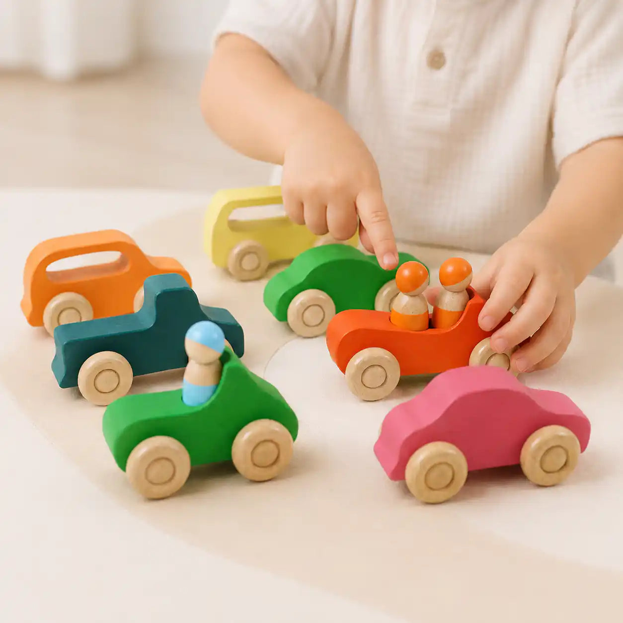 Small hands rolling the wooden rainbow car across a warm neutral surface