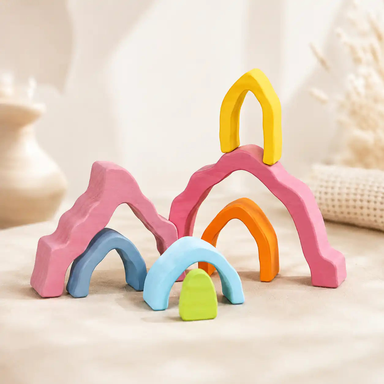 Small hands placing a wooden coral stacker piece onto the tower on a warm neutral surface